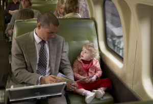 Father reading book to daughter (18-24 months) on train